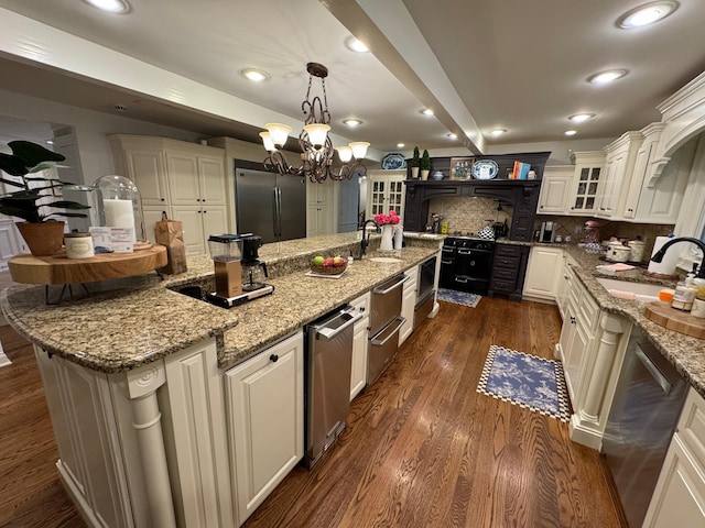 kitchen with sink, stainless steel appliances, dark wood-type flooring, and light stone counters