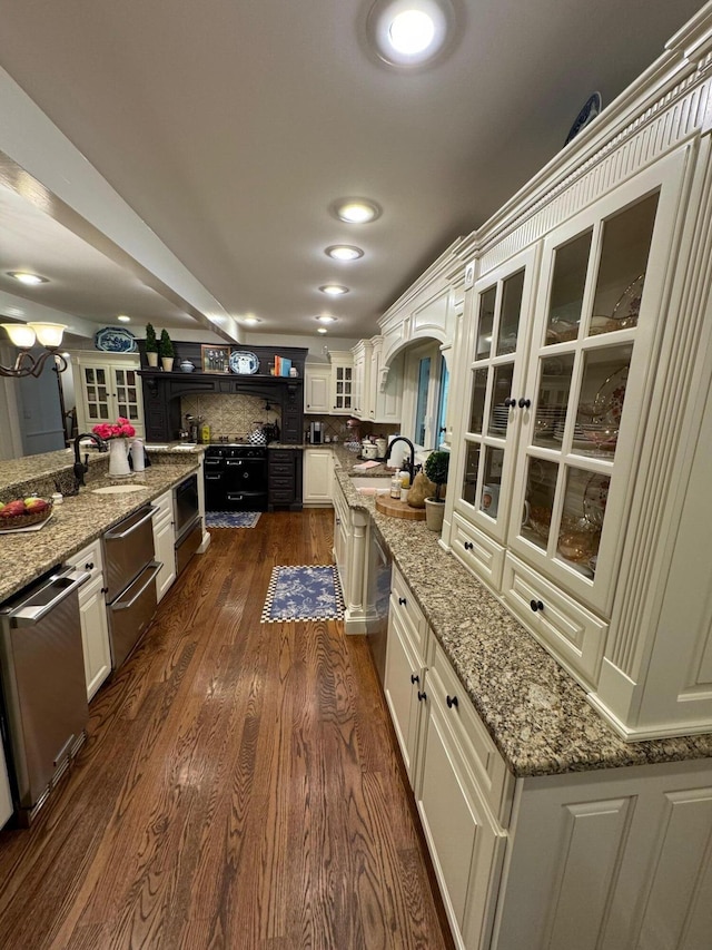 kitchen with sink, dishwasher, dark hardwood / wood-style floors, and light stone counters