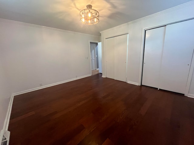 unfurnished bedroom featuring dark hardwood / wood-style floors, crown molding, and multiple closets