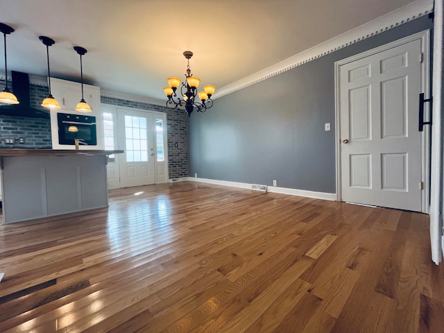 interior space featuring ornamental molding, brick wall, dark hardwood / wood-style floors, and a notable chandelier