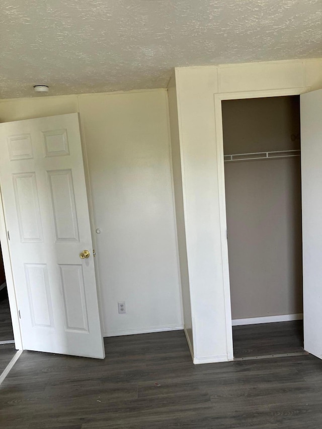 unfurnished bedroom with a textured ceiling, a closet, and dark hardwood / wood-style floors