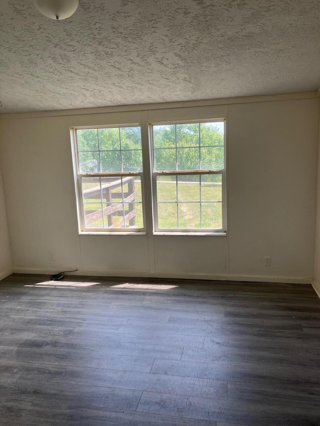 spare room featuring dark hardwood / wood-style flooring and a textured ceiling