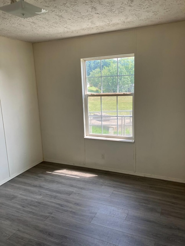 empty room with hardwood / wood-style flooring and a textured ceiling