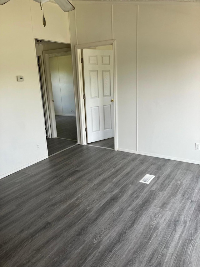 unfurnished room with ceiling fan, dark hardwood / wood-style floors, and a towering ceiling