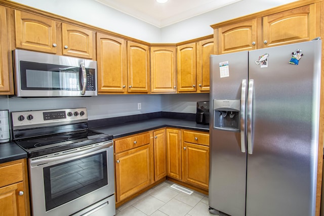 kitchen featuring light tile patterned floors, stainless steel appliances, and ornamental molding