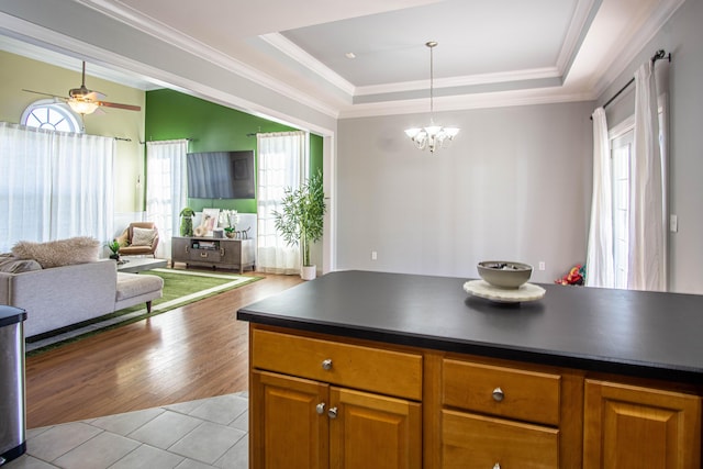 kitchen featuring ceiling fan with notable chandelier, light hardwood / wood-style floors, crown molding, and a tray ceiling