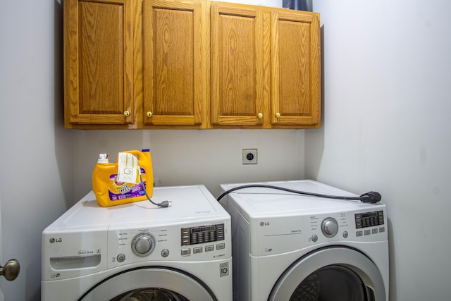 clothes washing area with washing machine and clothes dryer and cabinets