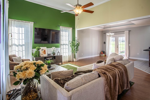 living room featuring hardwood / wood-style floors, ceiling fan with notable chandelier, crown molding, and french doors