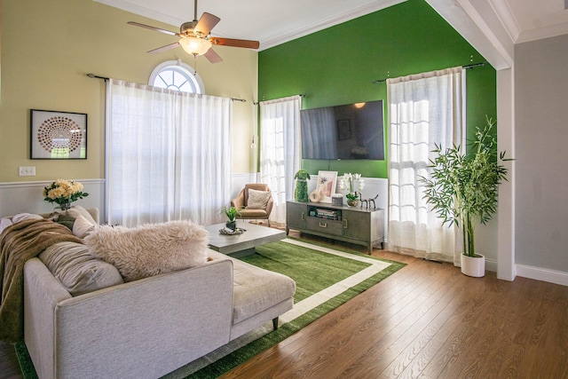 living room featuring crown molding, hardwood / wood-style floors, ceiling fan, and a high ceiling