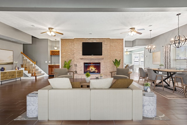 tiled living room featuring ceiling fan with notable chandelier, a wealth of natural light, brick wall, and a brick fireplace