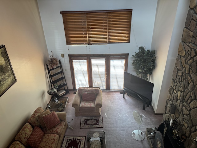 living area with a high ceiling, a fireplace, and carpet flooring