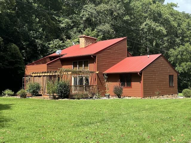 view of front facade featuring a chimney, metal roof, and a front yard