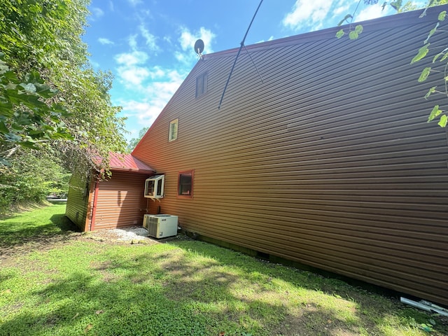 view of side of home with metal roof and a lawn