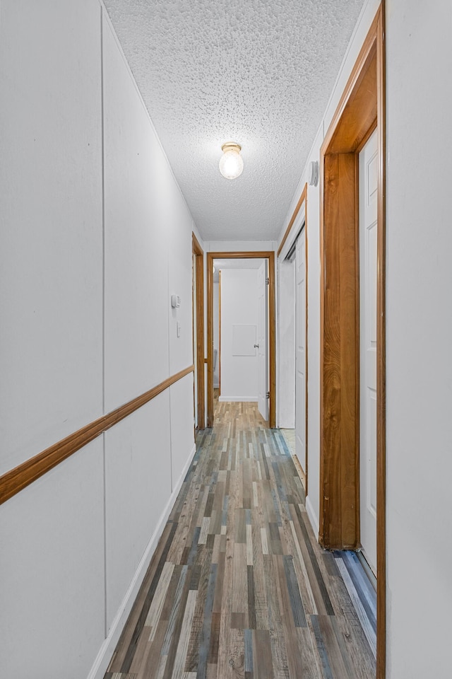 hall featuring a textured ceiling and dark hardwood / wood-style floors