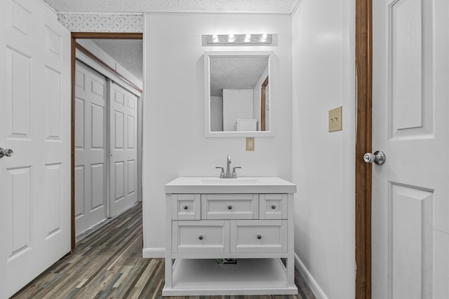 bathroom featuring a textured ceiling, wood finished floors, vanity, and baseboards