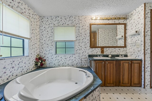 bathroom featuring tile patterned floors, a washtub, a textured ceiling, and vanity