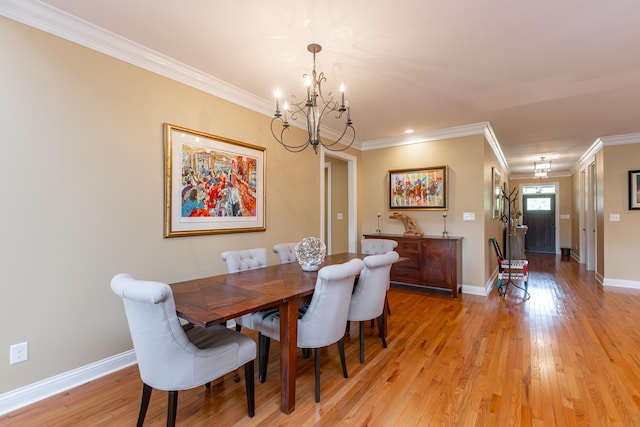 dining space with ornamental molding, an inviting chandelier, and light wood-type flooring