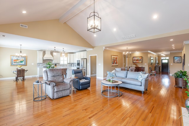 living room featuring crown molding, a healthy amount of sunlight, an inviting chandelier, and light wood-type flooring