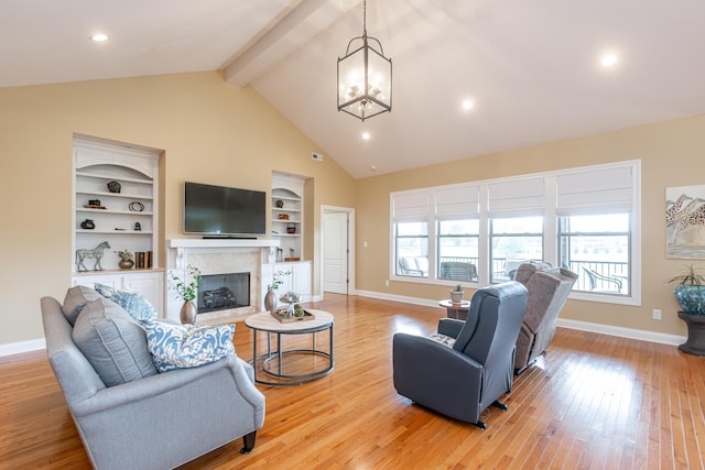 living room featuring a fireplace, built in shelves, a notable chandelier, light hardwood / wood-style flooring, and vaulted ceiling with beams