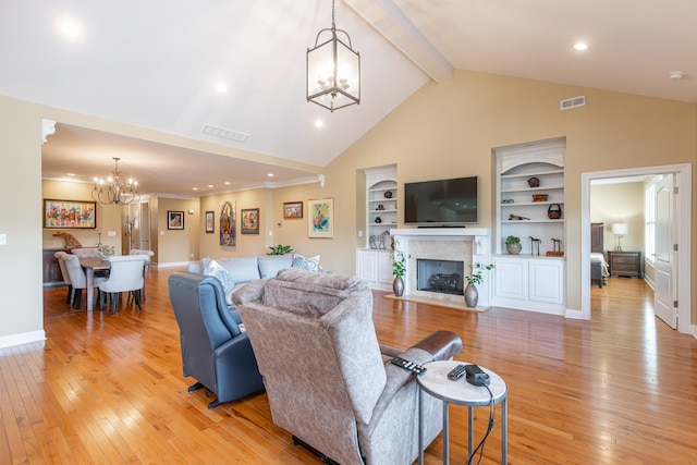 living room with beamed ceiling, a premium fireplace, a notable chandelier, light hardwood / wood-style floors, and built in shelves