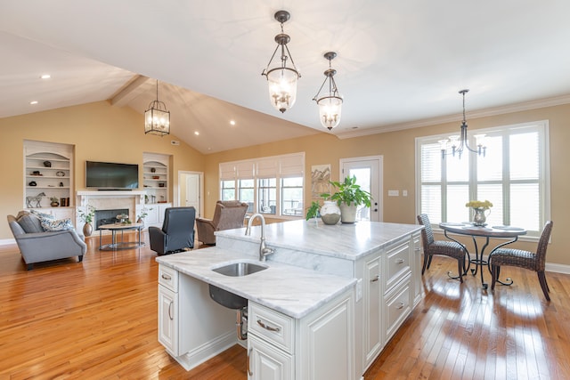 kitchen featuring a wealth of natural light, light wood-type flooring, white cabinetry, and a kitchen island with sink