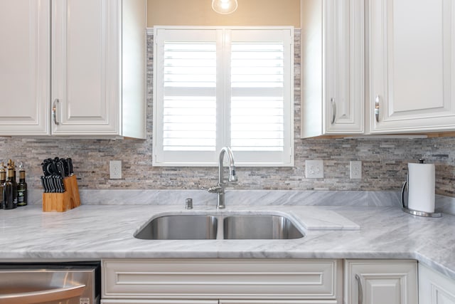 kitchen featuring backsplash, dishwasher, light stone countertops, white cabinetry, and sink