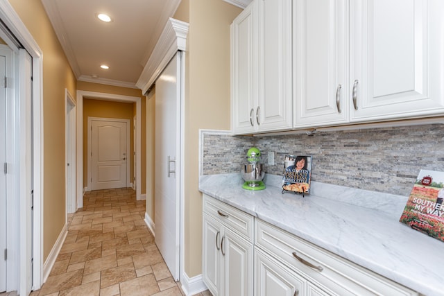 kitchen featuring white cabinets, backsplash, light stone counters, and ornamental molding