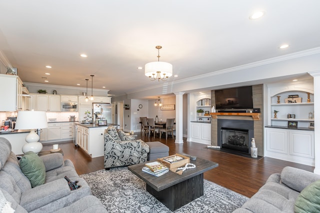 living room featuring dark hardwood / wood-style floors, crown molding, a notable chandelier, and sink