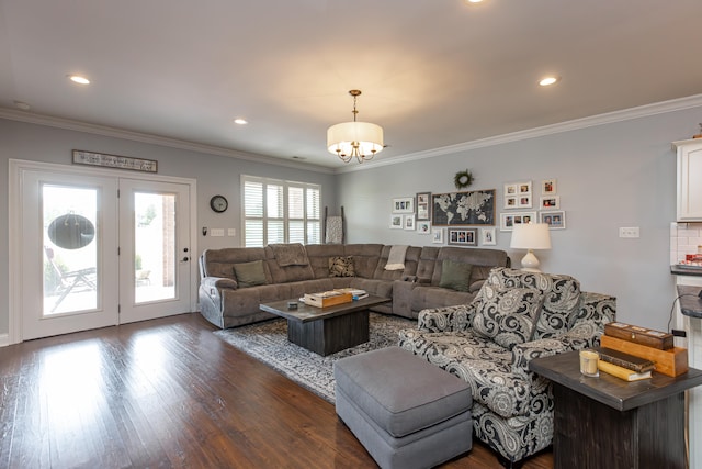 living room with dark wood-type flooring, a notable chandelier, and ornamental molding