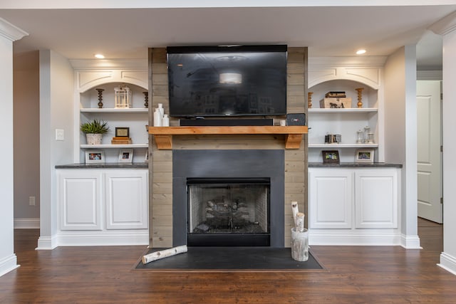 unfurnished living room featuring built in features, dark wood-type flooring, and a fireplace