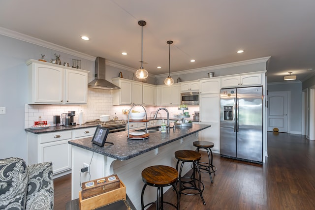 kitchen featuring decorative light fixtures, appliances with stainless steel finishes, dark hardwood / wood-style flooring, sink, and wall chimney exhaust hood