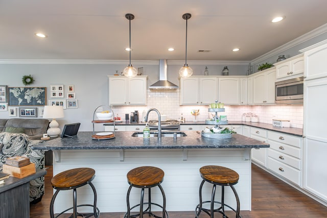 kitchen with dark hardwood / wood-style floors, hanging light fixtures, white cabinetry, wall chimney range hood, and stainless steel microwave