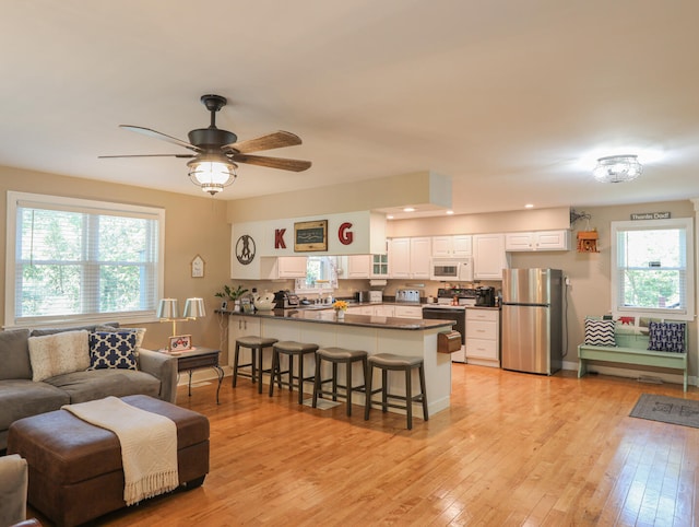 living room featuring light wood-type flooring, a wealth of natural light, and ceiling fan