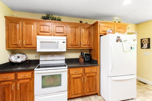 kitchen featuring dark countertops, white appliances, and brown cabinets