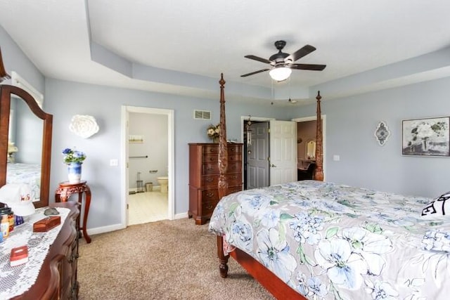 carpeted bedroom with connected bathroom, a ceiling fan, visible vents, baseboards, and a tray ceiling