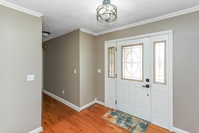 entryway featuring ornamental molding, a textured ceiling, baseboards, and wood finished floors