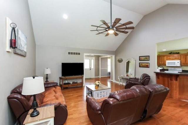 living area featuring ceiling fan, high vaulted ceiling, light wood-type flooring, and visible vents