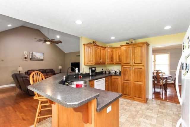 kitchen featuring dark countertops, open floor plan, a sink, and a peninsula