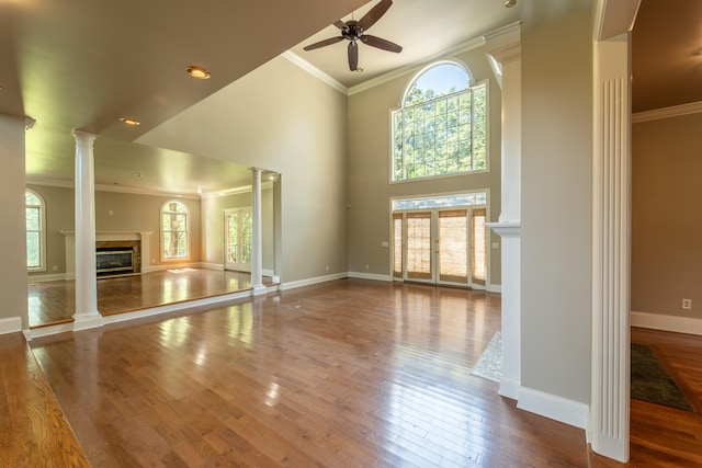 unfurnished living room with ceiling fan, plenty of natural light, and ornate columns