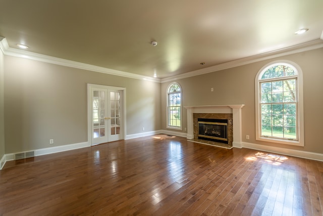 unfurnished living room featuring a premium fireplace, crown molding, a healthy amount of sunlight, and dark hardwood / wood-style flooring