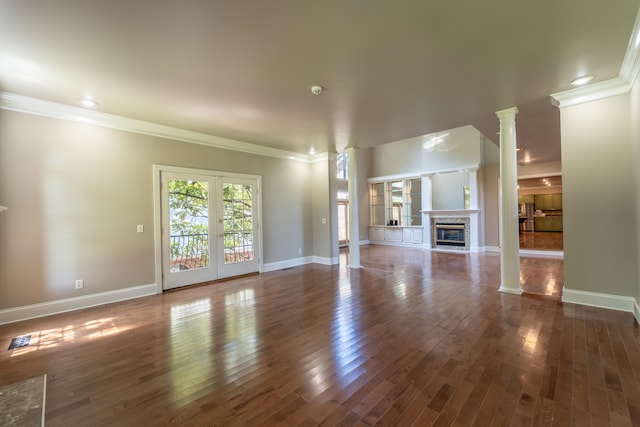 unfurnished living room with decorative columns, ornamental molding, and dark wood-type flooring