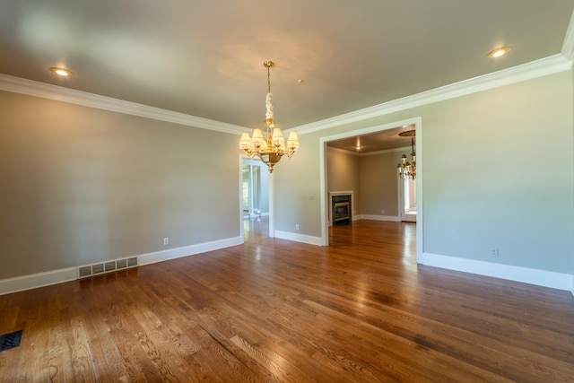 empty room featuring an inviting chandelier, crown molding, and dark hardwood / wood-style flooring