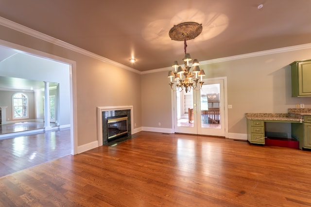 unfurnished living room featuring ornamental molding, french doors, hardwood / wood-style flooring, a notable chandelier, and a fireplace