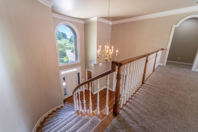 stairway with an inviting chandelier, ornamental molding, and hardwood / wood-style flooring