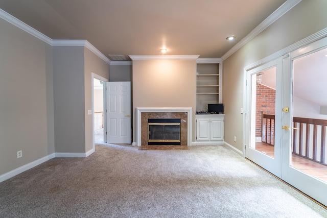 unfurnished living room with ornamental molding, light colored carpet, a fireplace, and french doors