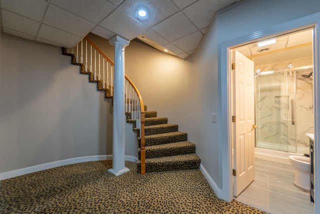 stairway featuring a drop ceiling and ornate columns