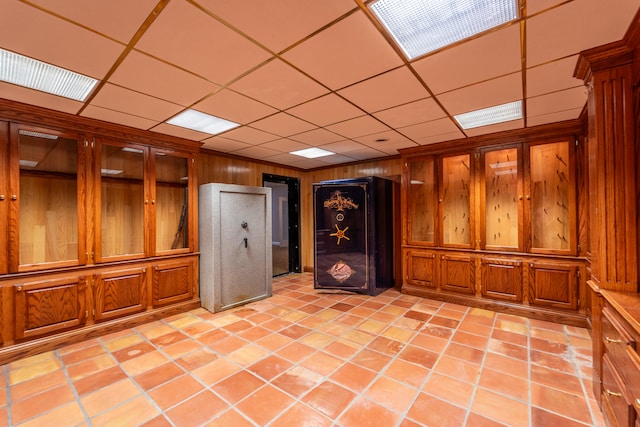 interior space with light tile patterned flooring, wooden walls, and a drop ceiling