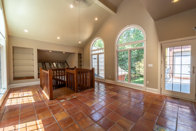 interior space with a healthy amount of sunlight, ceiling fan, dark tile patterned floors, and high vaulted ceiling