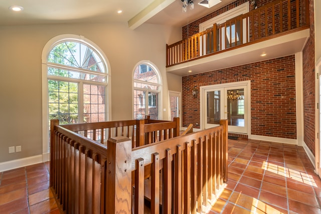 corridor featuring brick wall, beam ceiling, high vaulted ceiling, and tile patterned floors