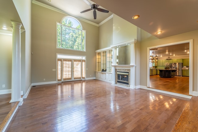 unfurnished living room with wood-type flooring, a fireplace, ceiling fan, and plenty of natural light